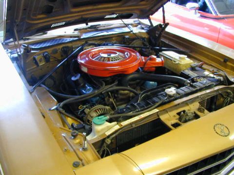 1979 Ford Bronco - Engine bay of a gold car, with a red car partially visible in the background.