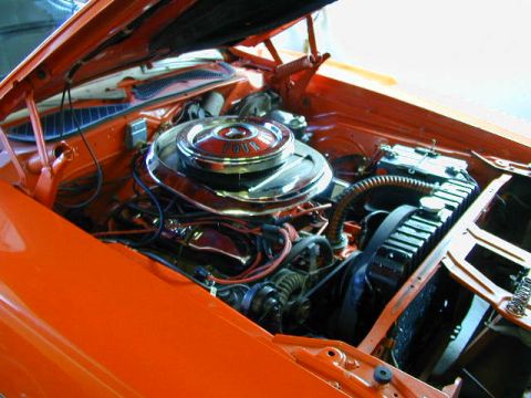 1979 Ford Bronco - The engine bay of an orange vehicle is shown, a chrome air cleaner with "FOUR" visible.