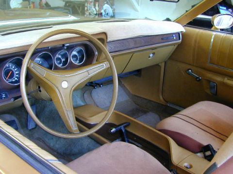 1979 Ford Bronco - The interior of a car shows tan upholstery, a steering wheel, and dashboard gauges. A website watermark is visible at the bottom right.