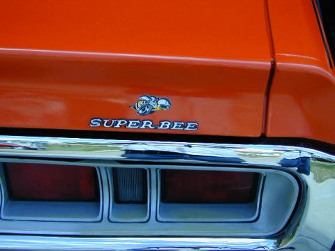 1979 Ford Bronco - Close-up of an orange car's rear, showing the 'Super Bee' emblem and part of a taillight.