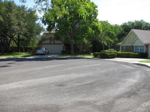 1983 Ford 427 - A silver sedan is parked in the driveway of a suburban home on a sunny day.