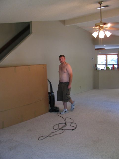 1983 Ford 427 - A man stands in a room with a vacuum cleaner and a large cardboard box, with a ceiling fan visible.