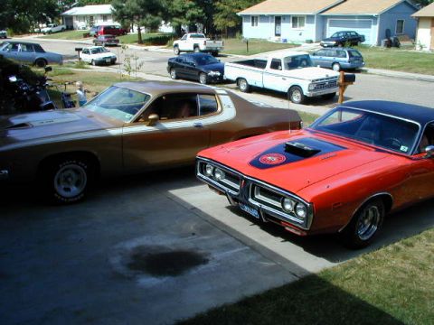 1979 Ford Bronco - Two vintage Mopar muscle cars, a red Dodge Charger and a brown Plymouth Duster, are parked side-by-side.