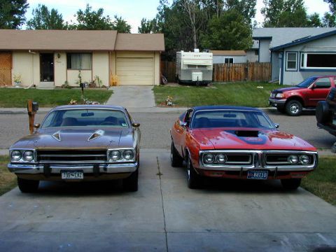 1979 Ford Bronco - Two classic Mopar muscle cars, a Plymouth Road Runner and a Dodge Charger, sit in a suburban driveway.