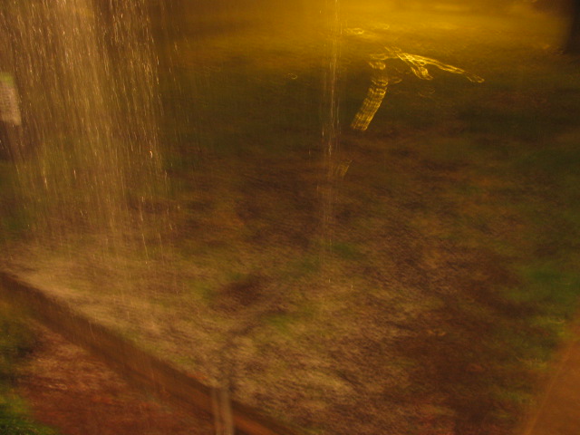 sprinkler head spraying water in a yard at night