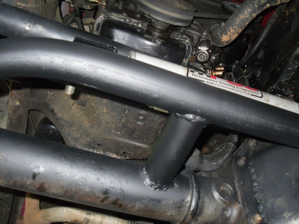 Black roll cage tubing over engine and suspension parts. A white tube with red text reads "Performance Steering Components"