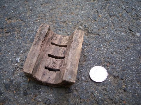 1971 Ford Ranchero - A weathered wooden component with carved slots is shown next to a coin on a dark, textured surface.
