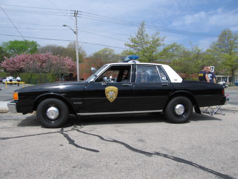 1991 Ford Crown Victoria - A black and white police car with a light bar on the roof is parked on the street.
