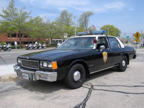 1991 Ford Crown Victoria - This police car, likely from the 1980s, is parked near a group of motorcycles.
