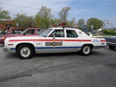 1991 Ford LTD Crown Victoria - patriotic red, white and blue vintage State Police sedan numbered 1776 sits in a parking lot at a car show.