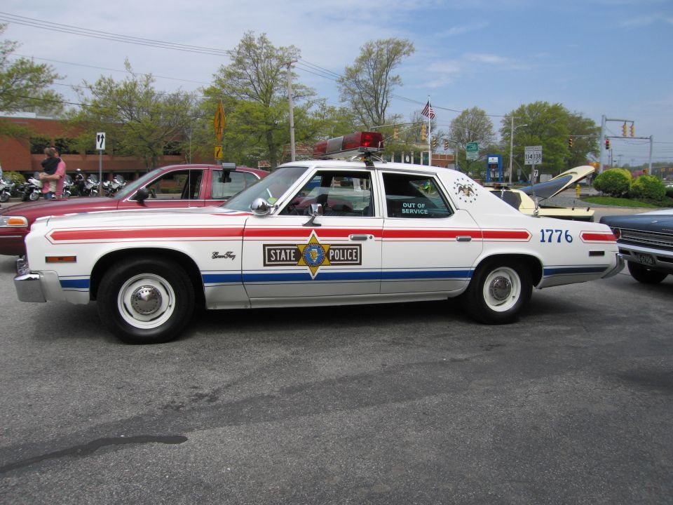 Vintage red-white-blue State Police sedan marked 1776 with roof lightbar