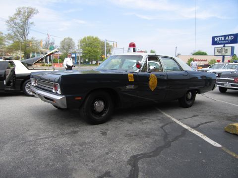 1991 Ford LTD Crown Victoria - dark-colored vintage State Police four-door sedan with a red dome light parked in a lot near a Rite Aid pharmacy.