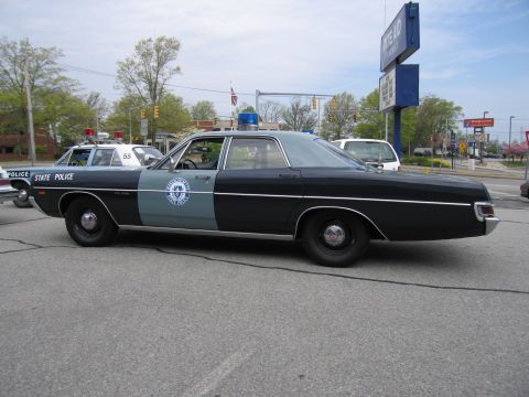 1991 Ford LTD Crown Victoria - Side view of a black-and-gray vintage State Police sedan with a blue dome light, another marked car (55) parked behind it.