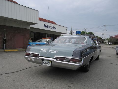 1991 Ford LTD Crown Victoria - Rear view of a vintage State Police sedan with license plate 86021 and a blue dome light parked outside a FedEx Office.