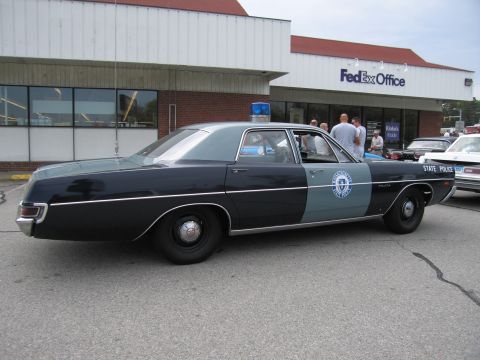 1991 Ford LTD Crown Victoria - Side view of a dark green and gray vintage State Police sedan with a blue dome light parked outside a FedEx Office.