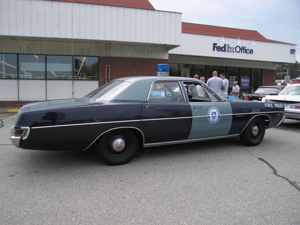 Dark green and gray State Police sedan, side view, outside FedEx Office