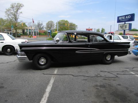 1991 Ford LTD Crown Victoria - Side profile of a black 1950s Ford two-door coupe with chrome side trim parked in a lot at a car show.