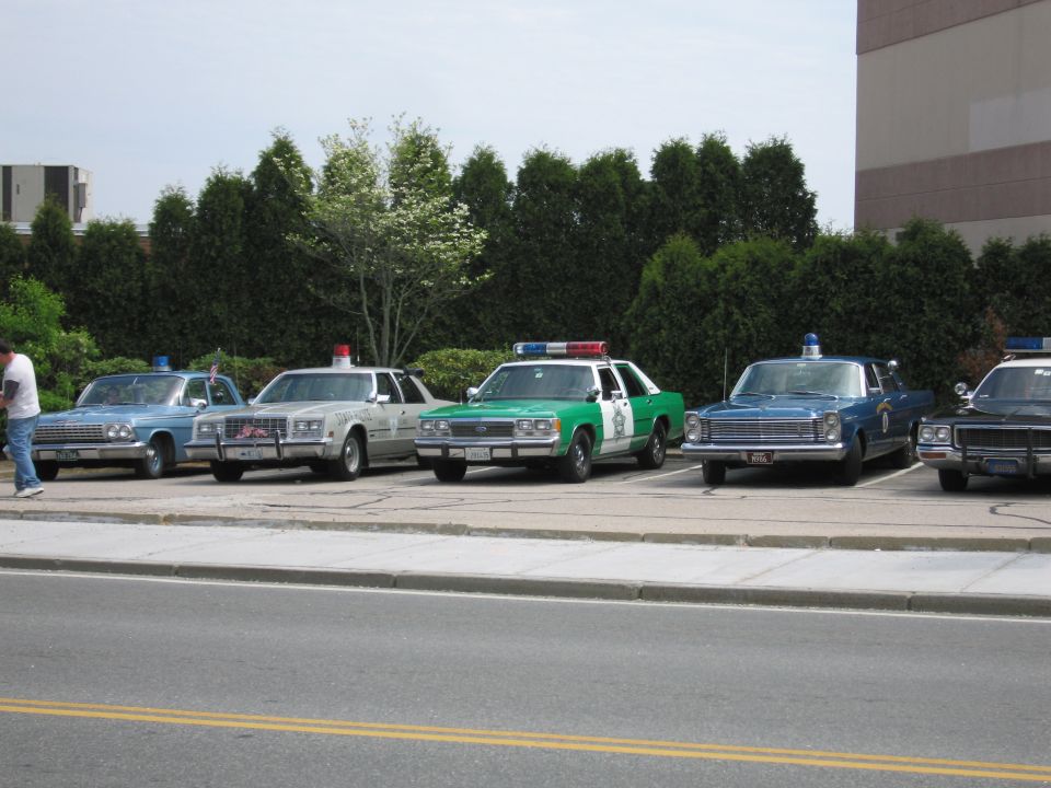 Line of vintage police sedans parked along a street curb