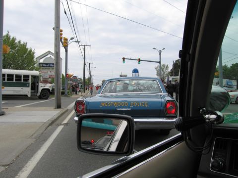 1991 Ford LTD Crown Victoria - blue Westwood Police vintage sedan with a dome light viewed ahead through a windshield at a street intersection.