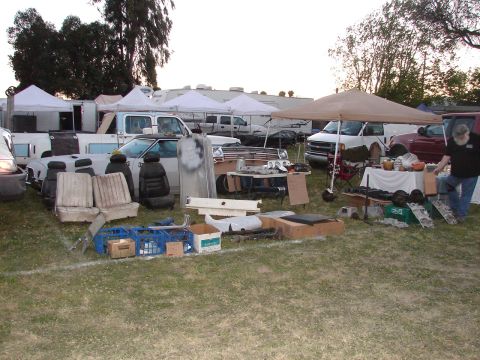 1973 Ford Ranchero - Outdoor market stall with car seats and auto parts for sale, multiple vehicles and tents visible.