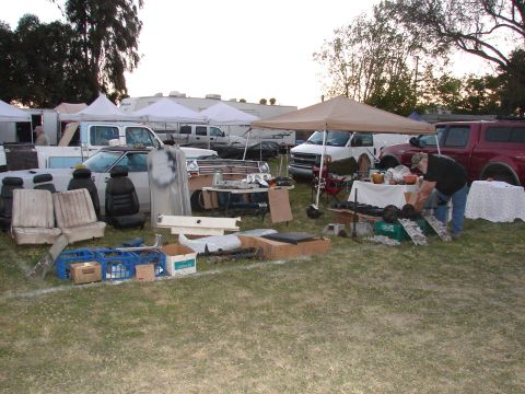 1973 Ford Ranchero - A variety of automotive parts are laid out for sale at an outdoor swap meet.