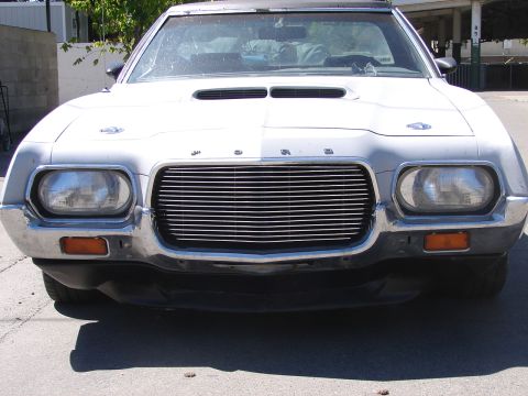 1973 Ford Ranchero - Head-on front view of a white 1970s Ford fitted with a horizontal-bar billet grille in place of the stock egg-crate insert, dual round head…