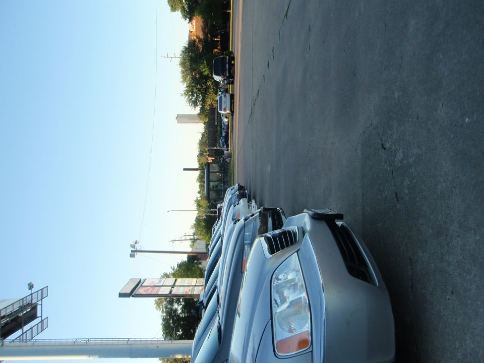 Several cars parked in a row, facing forward. A sign with "SUPERMOTORS" is visible on the front car
