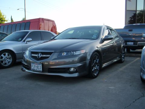 2003 Acura TL - A dark gray sedan is parked in a lot next to other vehicles and a bus.
