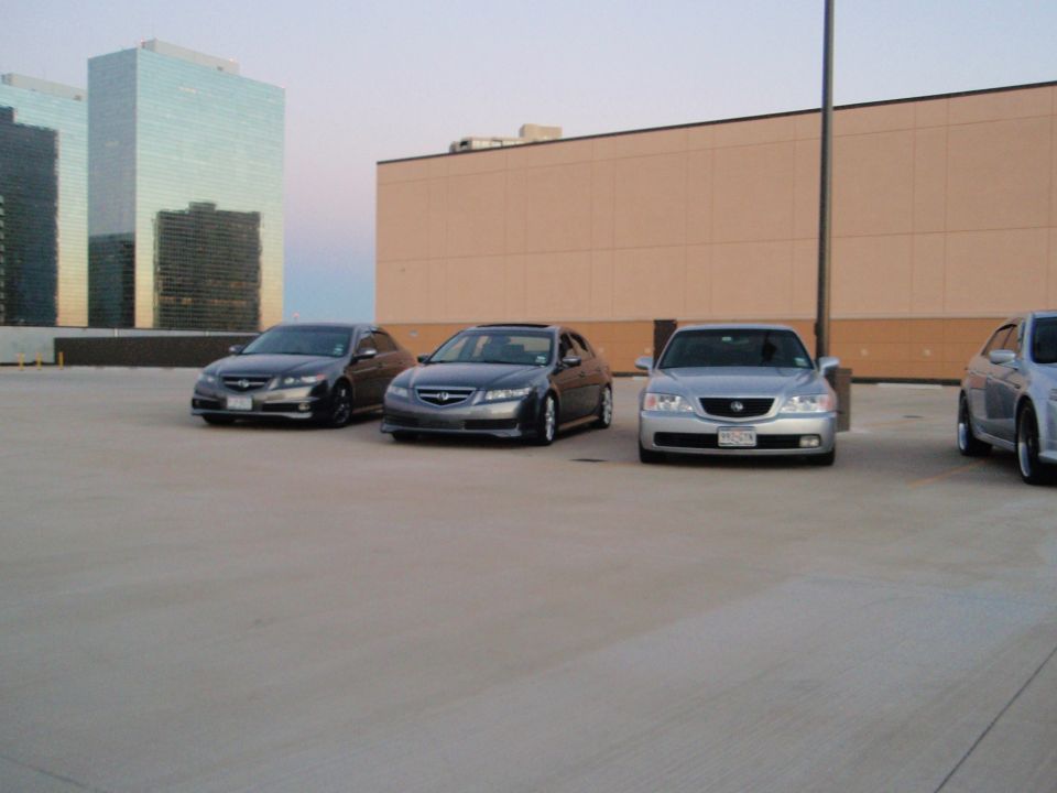 Three dark sedans and one silver sedan parked on a rooftop