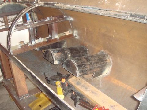 1992 Ford Bronco - In-progress sheet-metal fabrication inside a bare steel truck bed or body tub, with two half-round tube humps welded into the floor for dri…