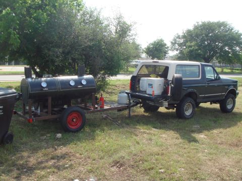 1992 Ford Bronco - Dark green Ford Bronco with a white removable hardtop parked on grass with its rear glass raised and tailgate down, loaded with coolers and…