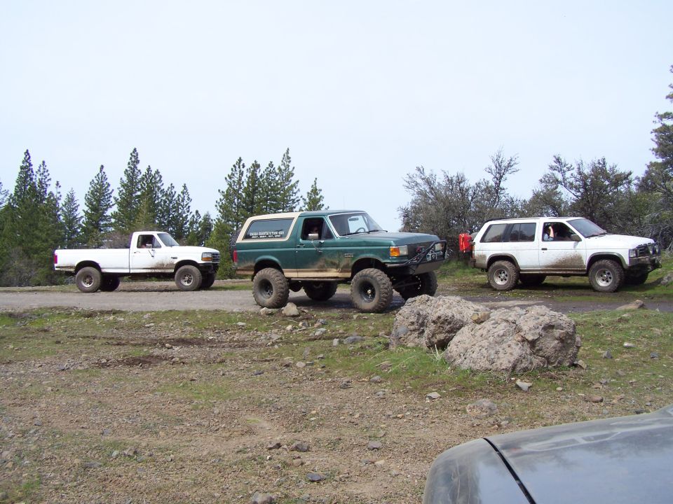 Three off-road vehicles parked on a dirt road with trees in the background