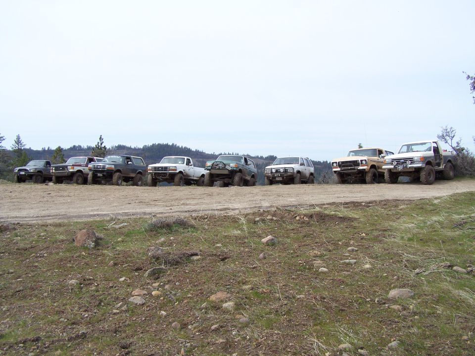 Line of off-road trucks and SUVs parked on a dirt road