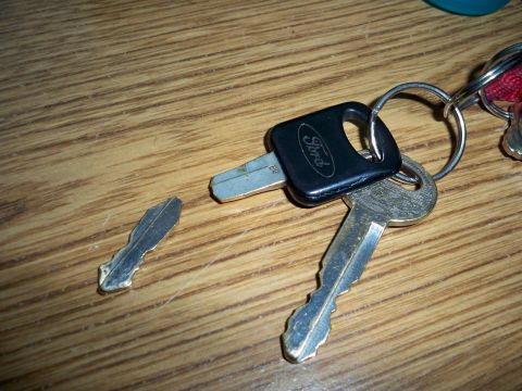 1994 Ford Bronco - A Ford key fob and a broken key lie on a wooden surface, suggesting a need for replacement.