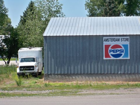 1994 Ford Bronco - A white box truck is parked beside a building with an 'Amsterdam Store' and Pepsi advertisement.