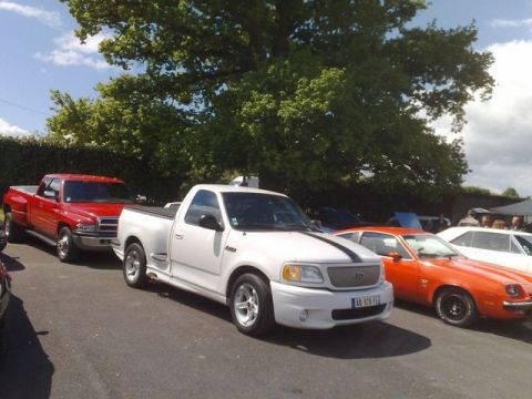 1991 Ford Crown Victoria - White 1999 Ford F-150 SVT Lightning pickup truck parked at an outdoor car show.