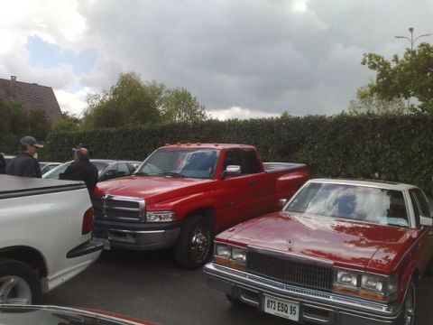 1991 Ford Crown Victoria - Several vehicles are parked outdoors under a cloudy sky, with a hedge in the background.