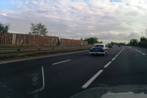 1991 Ford Crown Victoria - A classic two-tone sedan cruises down the highway under a cloudy sky.
