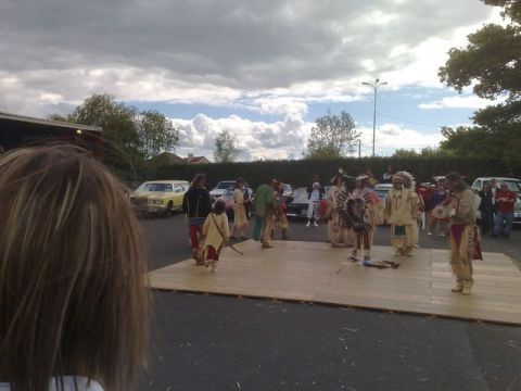 1991 Ford Crown Victoria - A group performs a cultural demonstration outdoors, with a variety of vehicles visible in the background.