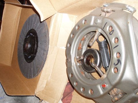 1979 Ford Bronco - A new clutch disc sits in its cardboard packaging beside the clutch pressure plate assembly, showing handwritten markings.