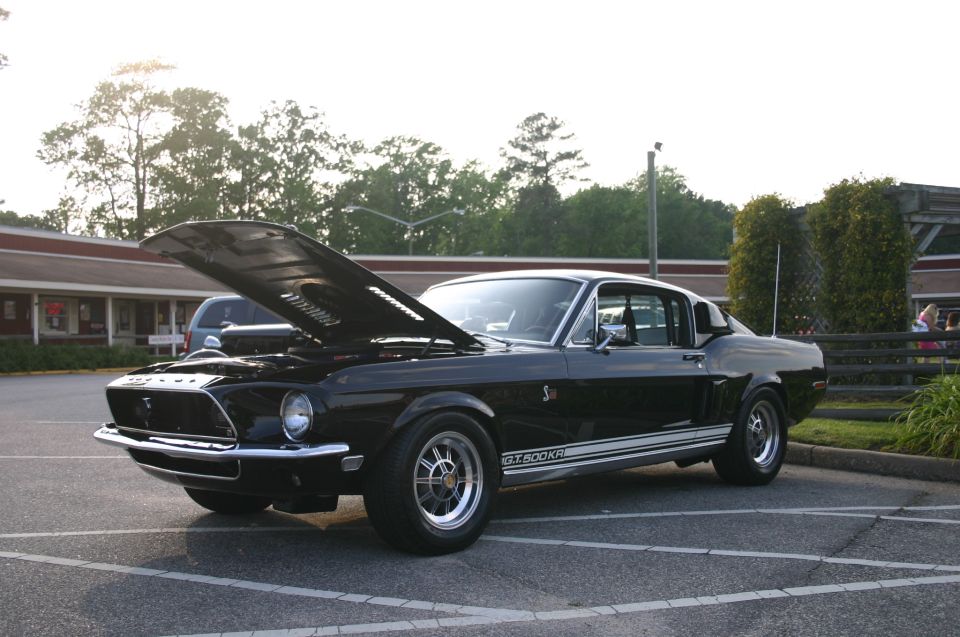 Black 1968 Shelby GT500KR with hood open parked in a lot