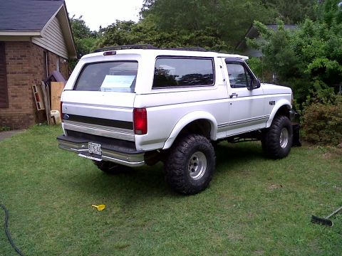 1996 Ford Bronco - This lifted white Ford Bronco has a rear 3/4 view, showing its aftermarket wheels and tires.