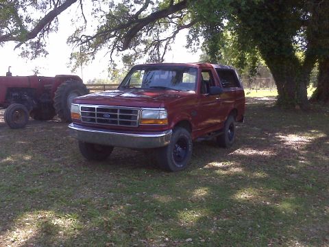 1996 Ford Bronco - This 1996 Ford Bronco is seen parked in a grassy area next to a tractor.