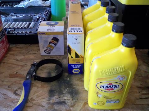 1994 Ford Bronco - Routine maintenance supplies including NAPA oil filters, Pennzoil oil, and a filter wrench are laid out on a workbench.
