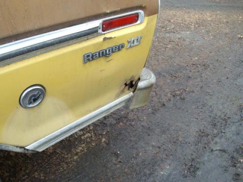 1976 Ford F-150 - The rear quarter panel of a yellow 1976 Ford F-150 Ranger XLT shows rust damage near the bumper and a fuel door.