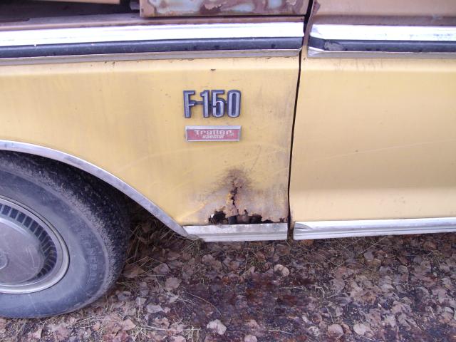 Rusted lower corner of a yellow Ford fender with F-150 and Trailer Special badges