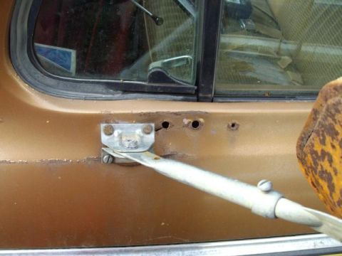 1976 Ford F-150 - The exterior of a truck door shows signs of rust and wear around the window frame and mounting points.
