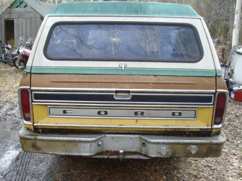 1976 Ford F-150 - The rear of a vintage Ford F-150 pickup truck, a two-tone paint job and a camper shell, is viewed from directly behind.