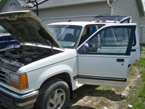 1994 Ford Explorer - The front of a white SUV is shown with the hood and driver's side doors open, revealing the engine and interior.