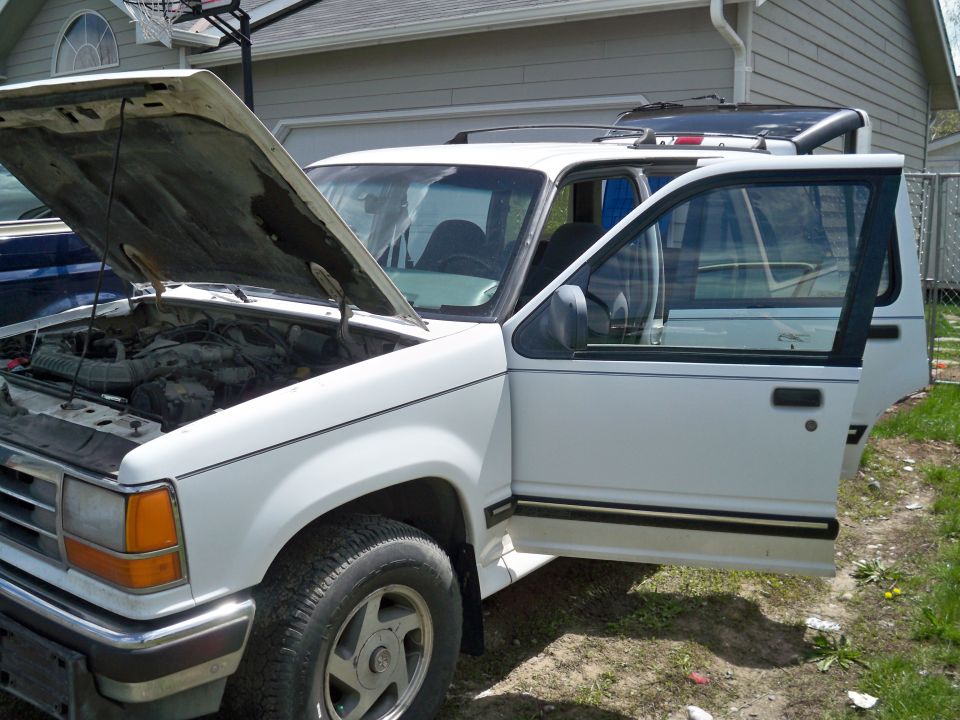 White SUV, hood and driver's side doors open, showing engine bay and interior